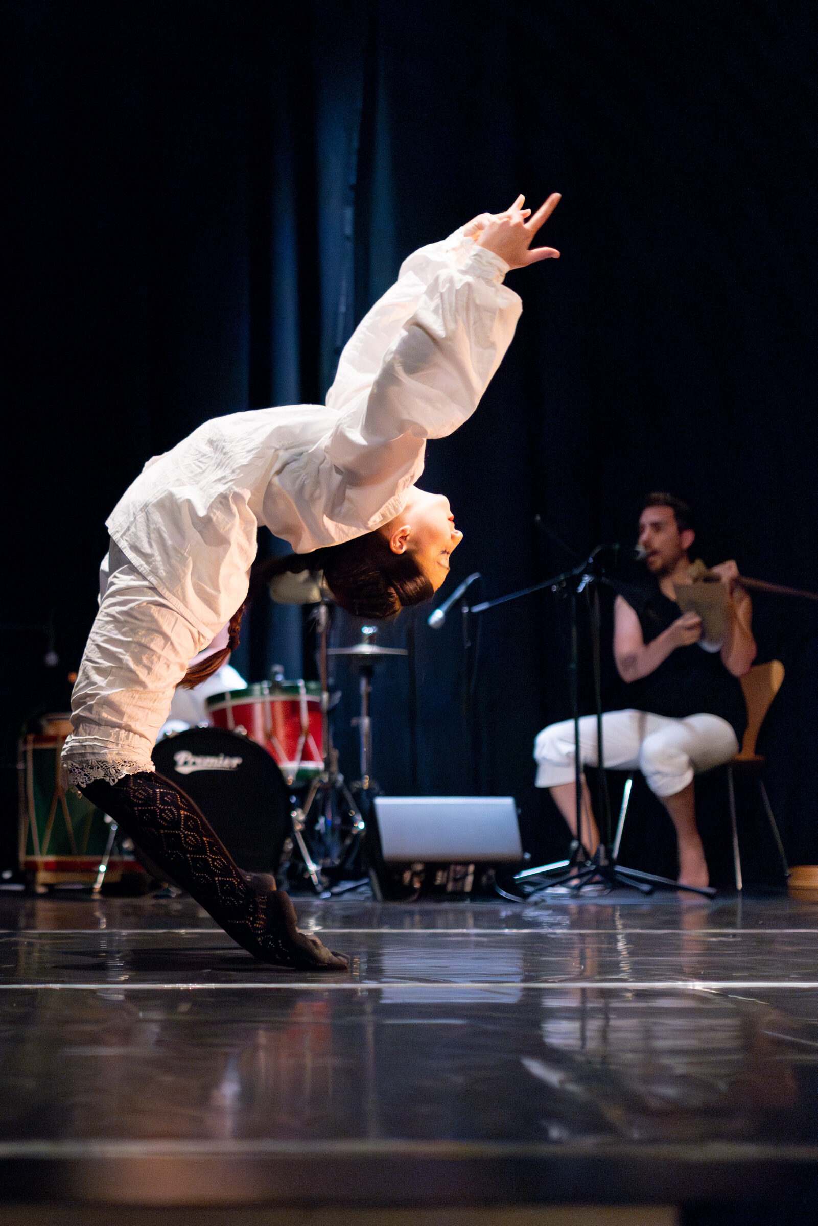 Bailarina facendo un arco cara atrás xunto aos músicos en directo