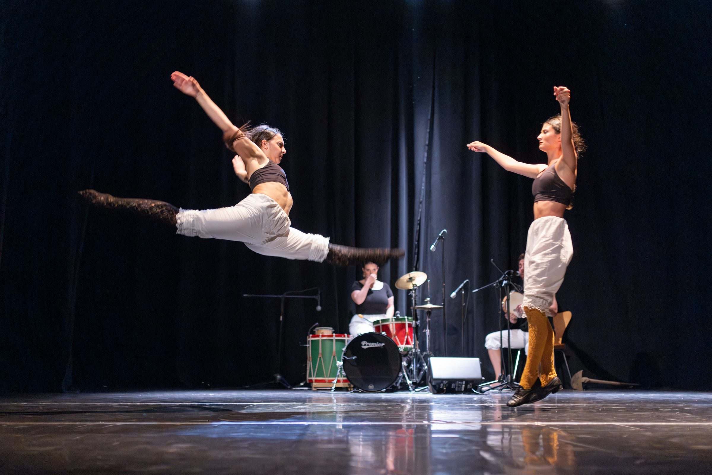 Bailarina saltando no aire mentres outra observa en escena